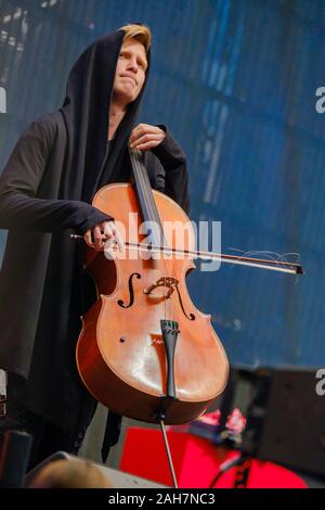 Mann in einem schwarzen Mantel mit Kapuze spielt Cello Stockfoto