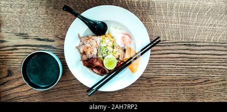 Miso Suppe mit asiatischen Nudeln mit Ei in Schale auf holztisch Hintergrund mit Stäbchen und Löffel Stockfoto