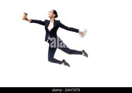 Schöne Geschäftsfrau holding Zeitung und Pappbecher während Levitierten isoliert auf weißem Stockfoto