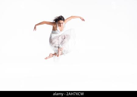 Schöne, anmutige Ballerina in weißem Kleid im Tanz Isolated On White Jumping Stockfoto