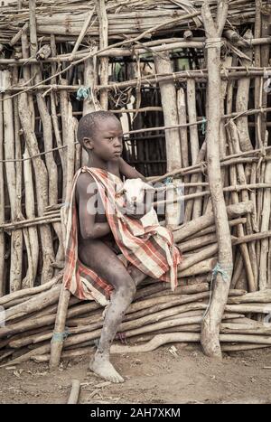 Gleichen, Tansania, 5. Juni, 2019: Masai junge halten Baby Ziegen aus ihrem Haus zu entkommen Stockfoto