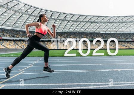 Junge afrikanische amerikanische Sportlerin auf Stadion in der Nähe von 2020 Schriftzug Stockfoto