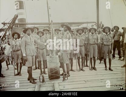 Nigeria, Kennzeichnung auf der Rückseite: 'Scout Meister Übergabe der Truppe, Badagry, 1928'. Ansehen oder Ändern der Zoll zwischen zwei Nigeria Pfadfinderführer ein Dampfer an Bord. Die beiden Scout Master Shake Hands über eine große Pauke, steht zwischen ihnen, von einem Publikum von mindestens 20 afrikanischen Pfadfinder, die alle Aufmerksamkeit stehend, 1928 beobachtet. 2000/098/2/39. Stockfoto