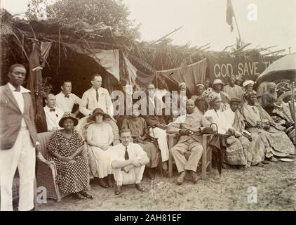 Nigeria, Kennzeichnung auf der Rückseite: "Empire Tag, Badagry 1924'. Informelle Gruppe Portrait von Afrikanern und Europäern im Empire Tag feiern im Badragry. Die Gruppe umfasst die europäischen Mitarbeiter von Miller Brüder und die Afrikanische Öl Muttern und ein afrikanischer Priester, 1924. 2000/098/2/29. Stockfoto