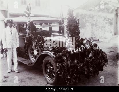 Nigeria, Kennzeichnung auf der Rückseite: "Tag des Gedenkens". Eine afrikanische Chauffeur steht neben einem Auto mit Laub und Union Flags für Tag der Erinnerung eingerichtet, [c 1920 s]. 2000/098/2/79. Stockfoto