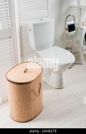 Innenraum der Weißen modernes Bad mit WC Schüssel in der Nähe von Folding Screen, Wäschekorb, WC-Bürste Stockfoto