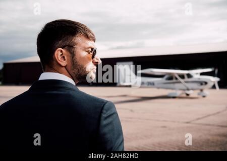 Ernst Kaufmann in formale Abnutzung und Sonnenbrille in der Nähe von Ebene Stockfoto
