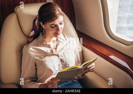 Attraktive Frau im Hemd Lesung buchen Sie im privaten Flugzeug Stockfoto