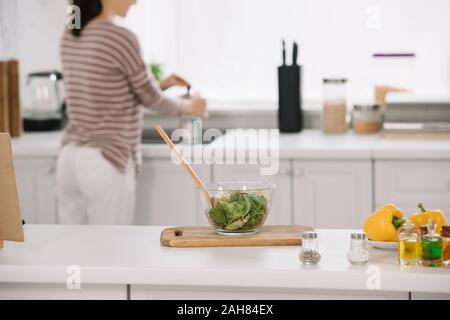 Selektiver Fokus der Schüssel mit frischem Salat und Frau Kaffee in Geysir/Teekocher Stockfoto