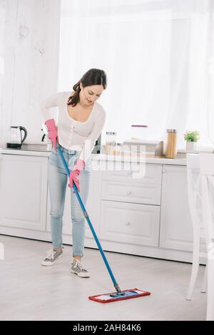 Attraktive, junge hausfrau Waschmaschine Fußboden in Küche mit Mop Stockfoto