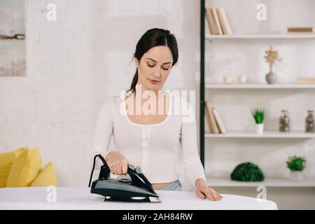 Schöne Hausfrau Lächeln beim Bügeln auf dem Bügelbrett Stockfoto