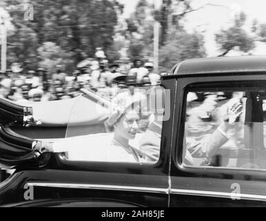 Kenia, eine offene Spitze auto Geschwindigkeit hinter der Kamera, die Prinzessin Elizabeth und der Herzog von Edinburgh Nairobi City Hall. Der Herzog von Edinburgh ist teilweise verdeckt durch die Fenster des Autos, kann aber seine linke Hand winken gesehen werden. Prinzessin Elizabeth wird gesehen, lächelnd auf die Menschenmenge, die säumen die Straße, Februar 1952. 2001/090/1/4/1/57. Stockfoto