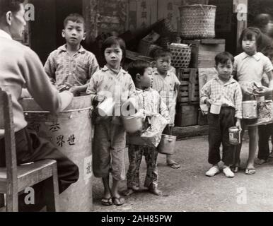 Hong Kong, Kinder Queuing für Lebensmittel, Hong KongCity Kinder queue mit tin-Container, warten Lebensmittelrationen von einer wohltätigen Organisation zu erhalten. Originalmanuskript Bildunterschrift: Kinder Queuing für eine Mahlzeit durch einige gemeinnützige Organisation, die 1963 zur Verfügung gestellt. 2005/010/1/11/40. Stockfoto