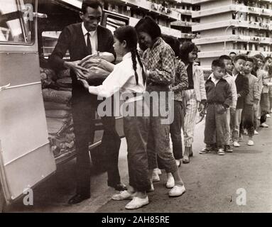 Hong Kong, Kinder Queuing für Lebensmittel, Hong KongCity Kinder Warteschlange außerhalb eine Umsiedlung Block in Kowloon, warten Lebensmittelpakete von der Rückseite der Wohltätigkeitsorganisation van zu erhalten. Originalmanuskript Bildunterschrift: Essen Warteschlange - Kowloon, 1963. 2005/010/1/11/39. Stockfoto