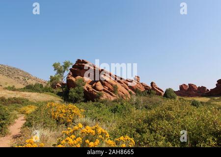 Rote Felsen ragen aus dem Boden von Sträuchern, Wildblumen, Gräser und Bäume auf der Trading Post Trail im Red Rock State Park, C umgeben Stockfoto