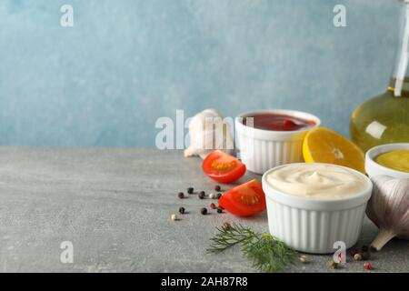 Satz von verschiedenen leckeren Saucen, Knoblauch, Tomaten, Zitrone auf grauen Hintergrund, Platz für Text Stockfoto