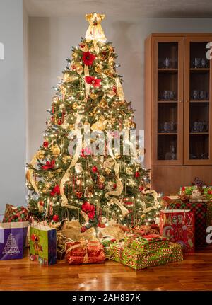 Innenraum des modernen Home mit Weihnachtsbaum dekoriert und beleuchtet und eingepackten Geschenke und Geschenke unter den Baum. Stockfoto