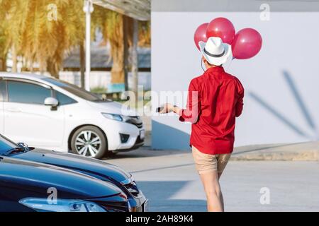 Rückansicht des homosexuellen Mann im roten Hemd mit roten Ballons vom Parkplatz der Partei am Nachmittag zu verbinden. Stockfoto