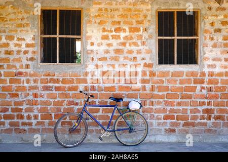 Blue Mountain bike geparkt lehnte sich gegen eine Mauer mit zwei Fenstern Stockfoto