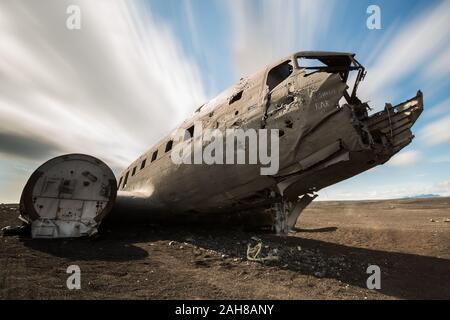 Niedrige Winkelansicht eines verlassenen DC-3-Flugzeugs, das in der isländischen Wüste liegt, vor einem blauen Sommerhimmel mit hängenden Wolken Stockfoto