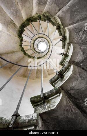 Geometrische Ansicht von unten des Treppenhauses einer alten und verwitterten Wendeltreppe Stockfoto