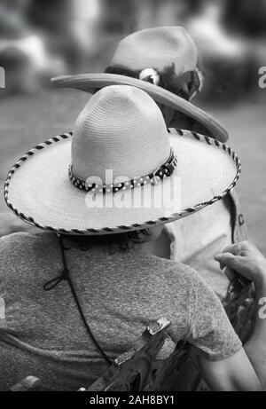 Ein älteres Paar mit großen Western Hüte sitzen und sprechen auf einer Bank in einem öffentlichen Park in Santa Fe, New Mexico. Stockfoto