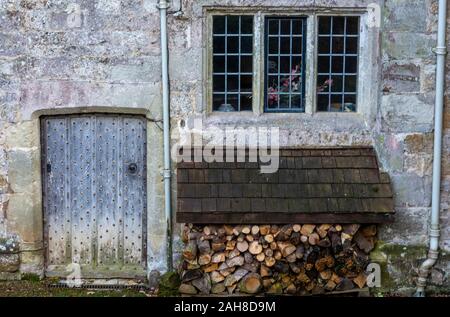 Anmelden oder Holz speichern und Fenster mit alten hölzernen Tür außerhalb eines alten Herrenhauses Bauernhaus. Stockfoto