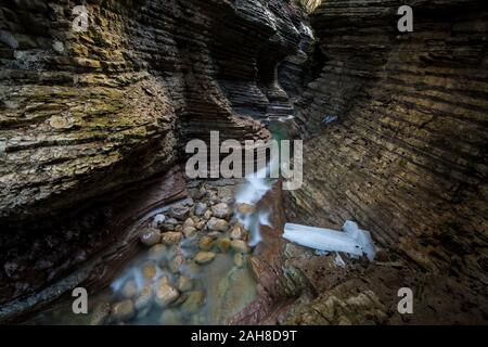 Weitwinkelansicht des Inneren eines roten Sandstein-Canyon mit einem Bach auf seinem Grund Stockfoto