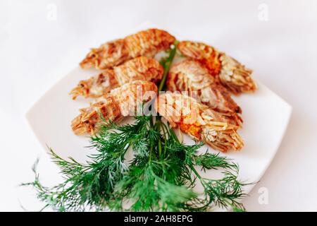 Shrimps und Dill auf einer Platte auf einem weißen Hintergrund. Stockfoto