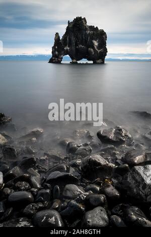 Symmetrische Weitwinkelansicht der Dursty-Dragon-Felsformation bei Ebbe und dunklen Kieselsteinen im Vordergrund Stockfoto