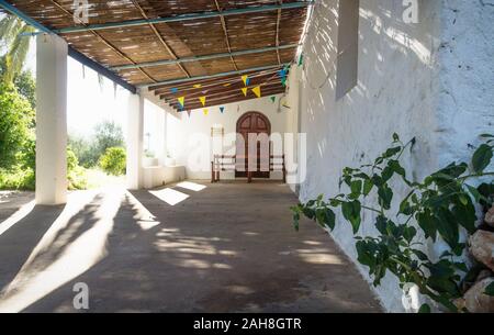 Eingang des abadoned Kirche Ermita de Sant Antoni y Sant Jaume mit Pflanzen- und dramatische Sonnenstrahlen in Gap Blanche, Spanien Stockfoto