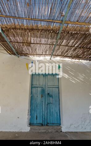 Blaue Tür aus Holz und Strohdach mit dramatischen Licht und Schatten bei abadoned Kirche Ermita de Sant Antoni Sant Jaume y vertikale in Gap Blanche, Al Stockfoto
