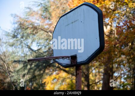 Abgenutzt, Basketballkorb in die Wälder gegen treibt und blauer Himmel Stockfoto