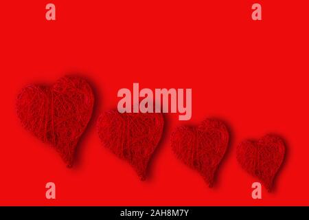 Herzen verschiedener Größen auf einem roten Hintergrund. Konzept der Valentinstag Stockfoto