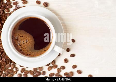 Americano und Kaffeebohnen auf weißem Holz- Hintergrund Stockfoto