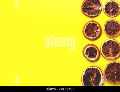 Scheiben getrocknete Orangen auf gelben Hintergrund. Neues Jahr oder Weihnachtskarte. Stockfoto