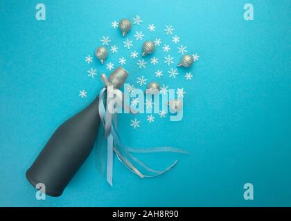 Festliche Champagner Flasche mit bunten glitzernden Sterne Spritzer auf blauem Hintergrund. Minimal party Konzept. Stockfoto