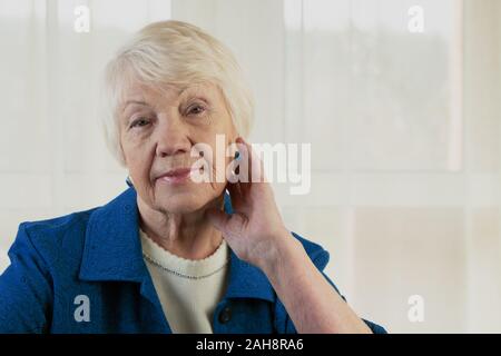 Schöne ältere Frau in die Kamera schaut mit einer warmen, freundlichen Lächeln und aufmerksamen Ausdruck Stockfoto