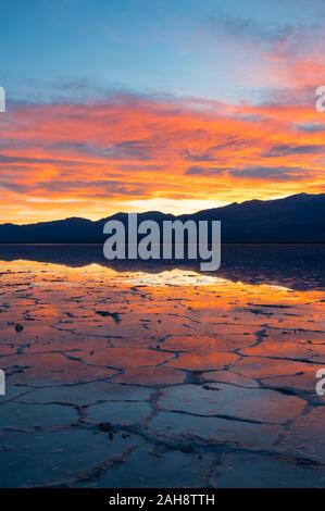 Farbenfroher Sonnenuntergang über einem überfluteten Badwater Basin im Death Valley National Park mit Spiegelungen der Berge im Wasser in Kalifornien am 14. Dez. 2019 Stockfoto