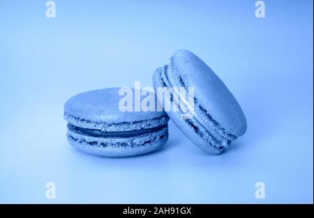 Rosa und Violett Makronen auf ein modisches Coral Hintergrund close-up, Französisch cookies als Wohltat für den Urlaub, getönten trendy Classic blau Farbe für Ihr Stockfoto