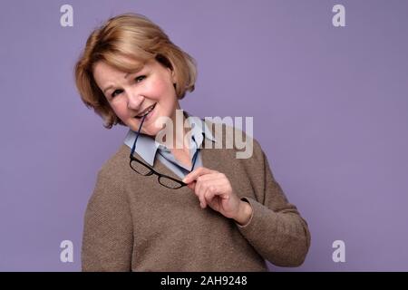 Portrait von fröhlichen älteren Frau gegen dunkle Wand lehnt Stockfoto