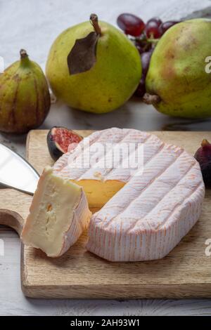 Rundes Stück französischer Käse Fleur Rouge aus Kuhmilch hergestellt als Dessert serviert mit frischen Feigen und Birnen Nahaufnahme Stockfoto