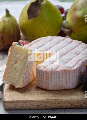 Rundes Stück französischer Käse Fleur Rouge aus Kuhmilch hergestellt als Dessert serviert mit frischen Feigen und Birnen Nahaufnahme Stockfoto