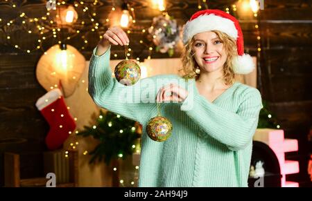 Vorbereitung Dekorationen im Voraus. Girl santa hut halten Sie die goldenen Kugeln Dekorationen für den Weihnachtsbaum. Dekoratives Zubehör Shop. Ihre Weihnachtsdekoration prüfen und ersetzen Sie etwas abgenutzt ist. Stockfoto