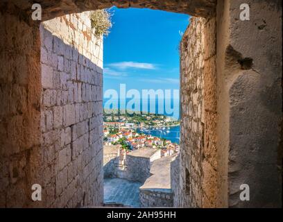 Ein Blick auf den wunderschönen Hafen von Hvar durch einen schmalen Eingang Passage in der mittelalterlichen Festung oberhalb der Stadt gesehen. Stockfoto