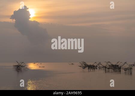 Traditionelle thailändische Bambus Angeln Werkzeuge mit nicht identifizierten silhouette Menschen auf dem Boot bei Sonnenaufgang am Morgen in Pakpra, Phatthalung, Thailand Stockfoto