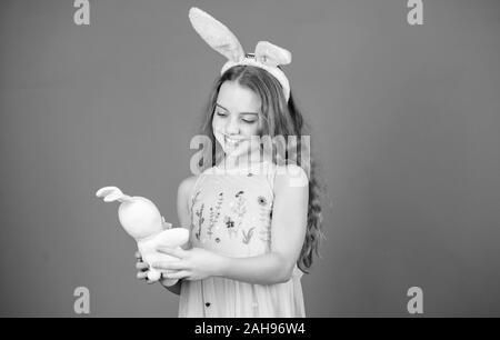 Ruhe und frohe Ostern. Kleines Mädchen und Kaninchen Spielzeug. Kleine Mädchen in Rabbit Ears mit Ostern Spielzeug. Kleines Kind in Osterhasen Stil spielen mit Spielzeug. Kleines Kind mit niedlichen Spielzeug. Osterhase Hase. Stockfoto