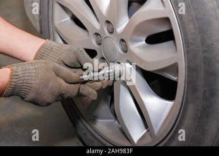 Der Vorgang des Änderns von Reifen auf ein Auto vor der Saison. Der Vorgang, bei dem das Rad aus dem Auto. Austausch der Gummi vor der Saison. Stockfoto