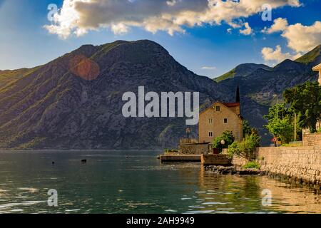 Altes Steinhaus in der Bucht von Kotor oder Boka Kotorska und die umliegenden Berge mit kristallklarem Wasser auf dem Balkan, in Montenegro an der Adria Stockfoto