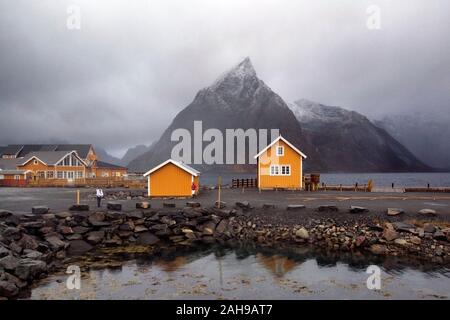 Traditionelle gelb Rorbu Kabinen mit Olstinden Mountain Peak in der Dämmerung im Herbst, Dorf von Sakrisoy, Lofoten Inseln, Norwegen Stockfoto